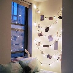 a bedroom with lights strung from the ceiling and pictures on the wall above the bed