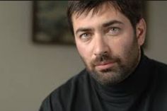 a close up of a person wearing a black turtle neck shirt and looking at the camera