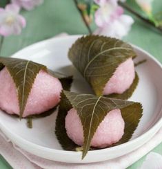 three leaf shaped desserts on a plate with pink powdered sugar and green leaves