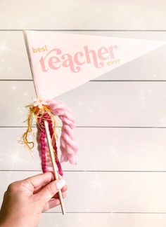 a person holding a pink and white flag with the word teacher over it