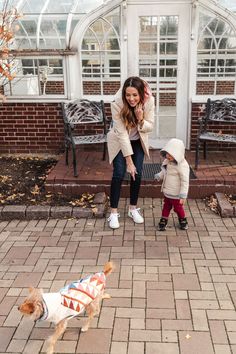 a woman standing next to a little boy on top of a brick floored walkway