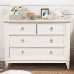 a white dresser with flowers and pictures on top