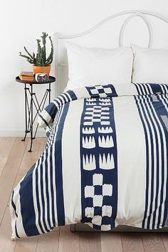 a bed with blue and white striped bedspread on top of wooden flooring