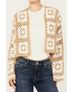 a woman is wearing a crocheted jacket and jeans