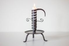 a metal candle holder with a lit candle on it