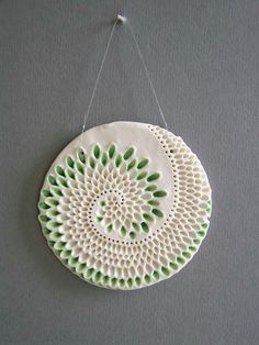 a white and green ceramic decoration hanging on a wall