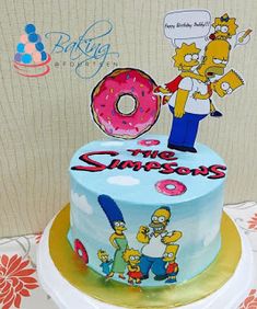 a birthday cake decorated with the simpsons characters and a donut on top is sitting on a table