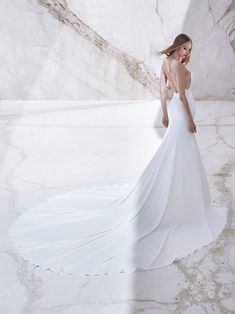 a woman in a white wedding dress is standing on the ground with her back to the camera