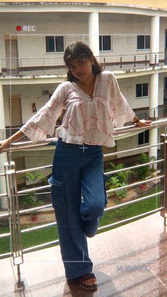 a woman standing on top of a balcony next to a building