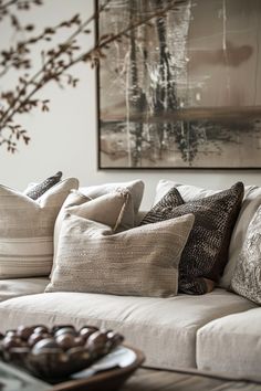 a living room filled with lots of pillows on top of a white couch next to a painting