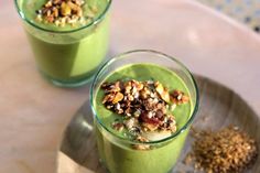 two glasses filled with green smoothie and nuts