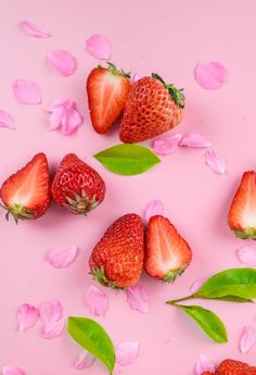 strawberries with leaves and petals on a pink background