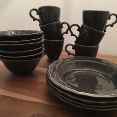 a stack of black dishes sitting on top of a wooden table