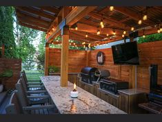 an outdoor kitchen with grill and television on the wall