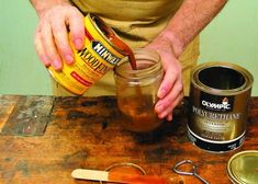 a man pouring something into a jar on top of a wooden table next to other items