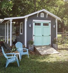 two lawn chairs sitting in front of a shed with a blue door and white trim