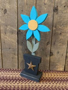 a small blue flower on top of a wooden block with a star in the middle