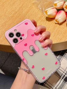 a person holding a pink and gray phone case with heart shapes on it's side