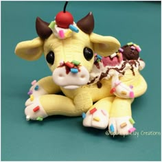 a small toy cow sitting next to an ice cream sundae on a blue surface