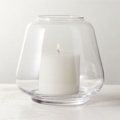 a lit candle in a glass vase on a table