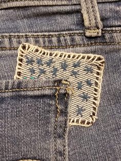 the back pocket of a pair of blue jeans with an embroidered patch on one side