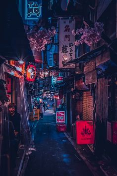 an alley way with neon signs and people walking down it