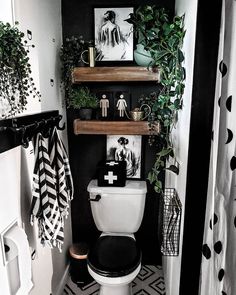 a bathroom decorated in black and white with plants on the shelves above the toilet bowl