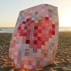 a large patchwork quilt sitting on top of a sandy beach