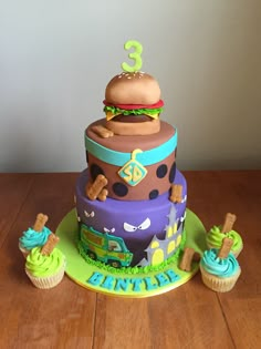 a birthday cake made to look like a burger and cupcakes with the number 3 on top