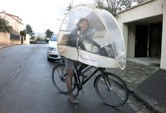 a woman is riding her bike with an umbrella on it's back and the front wheel