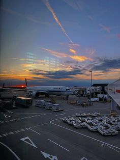 an airport tarmac at sunset with airplanes parked on the runway and in the background