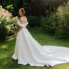 a woman in a wedding dress standing on the grass