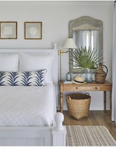 a white bed sitting next to a wooden table with a mirror on top of it