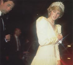 a woman in a white dress and tiara standing next to a man