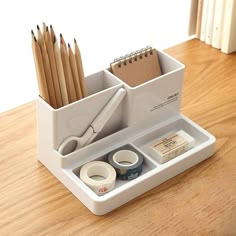 a white desk organizer with pencils, tape and scissors in it on a wooden table