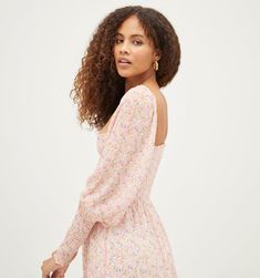 a woman with curly hair wearing a pink floral dress