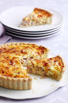 a quiche on a plate next to plates with one slice missing from the pie