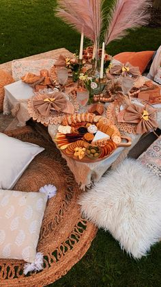 a table set up for a party with food and flowers on it in the grass