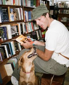 a man reading a book to his dog in front of a bookshelf full of books