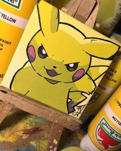 a painting of a pikachu on a easel next to some paint cans