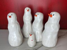 five white ceramic birds sitting next to each other on a counter top in front of a red door