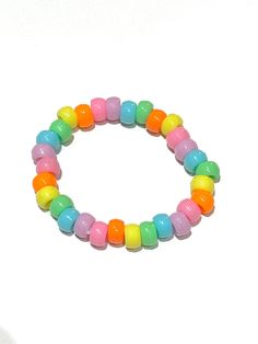 Beaded pastel rainbow bracelet (kandi) made with clear stretchy string. Rainbow Colorful Beads Plastic Jewelry, Rainbow Plastic Jewelry With Colorful Beads, Cute Rainbow Stretch Bracelet With Round Beads, Playful Rainbow Stretch Bracelet With Round Beads, Cute Rainbow Stretch Bracelet With Colorful Beads, Cute Rainbow Colorful Beads Stretch Bracelet, Kidcore Bracelet, Rainbow Bracelet, Rainbow Beads