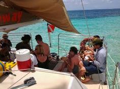 people are sitting on the back of a boat in the clear blue water while others watch