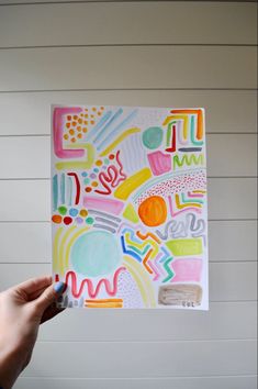 a person holding up a piece of art that has been drawn on paper and colored