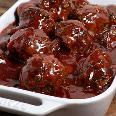 meatballs covered in marinara sauce in a white casserole dish on a wooden table