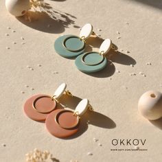 three pairs of earrings sitting on top of sand