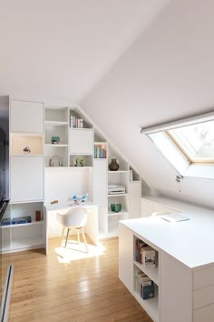 an attic bedroom with white furniture and open shelving units on the wall, along with a skylight