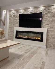 a living room with a fireplace and tv mounted on the wall, along with hardwood floors