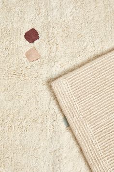 a close up of a white blanket on a bed with a red and brown patch