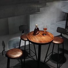 three chairs and a table with two wine bottles on it in a dimly lit room